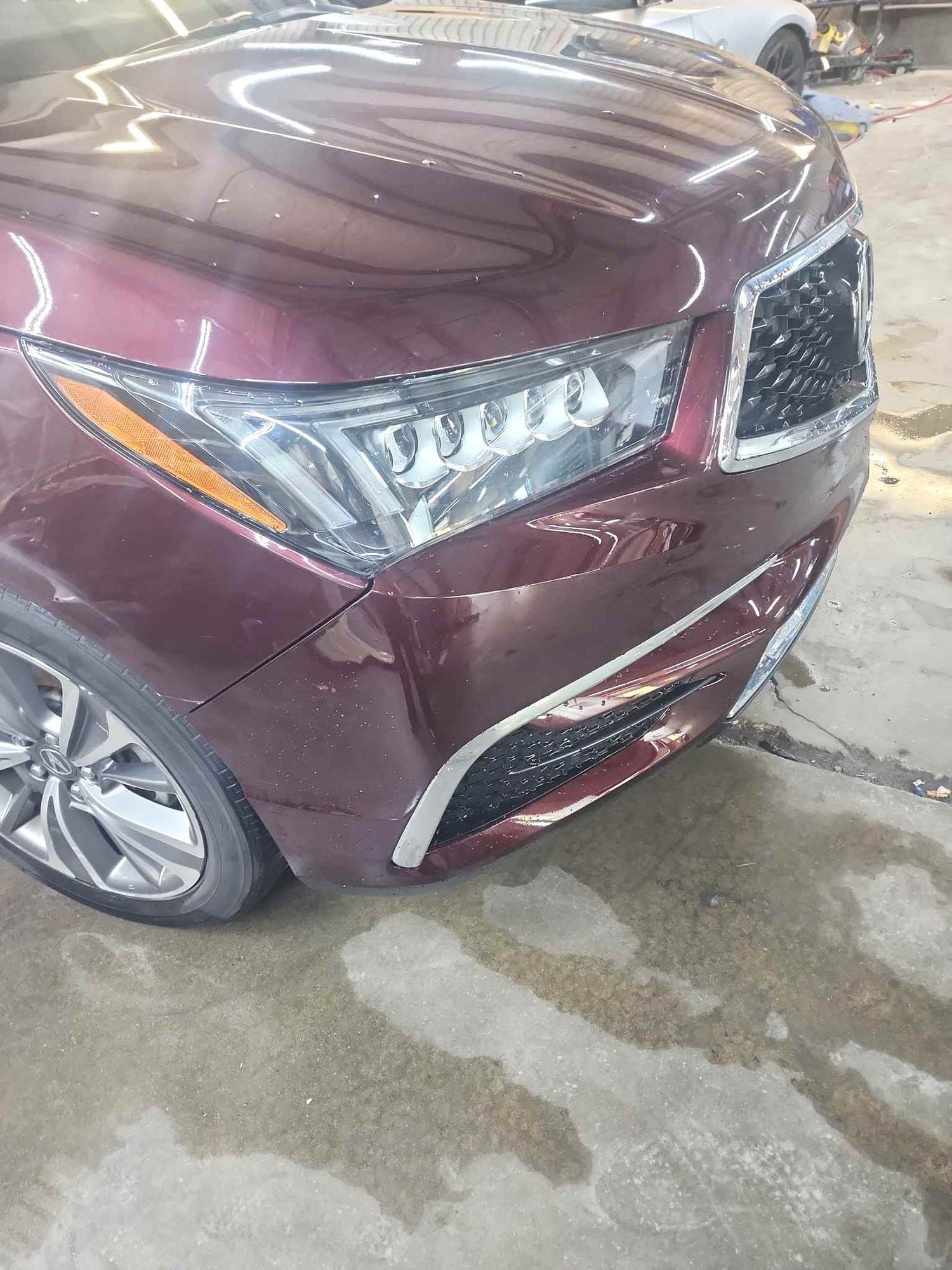 SUV, front corner: after repair. The dark red SUV after repair with the headlight and bumper corner restored