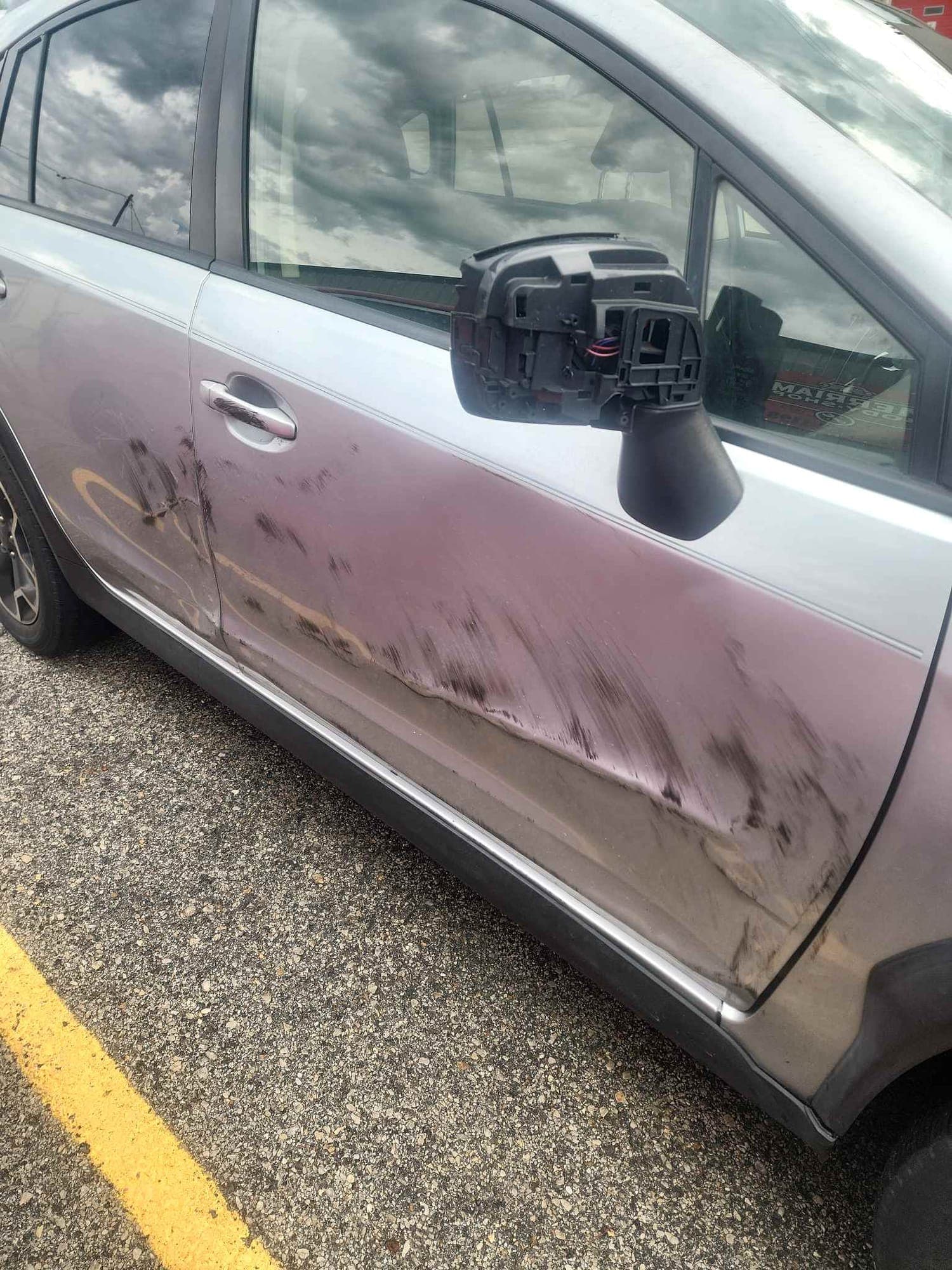 Crossover, door: before repair. A silver crossover with scrapes along the door