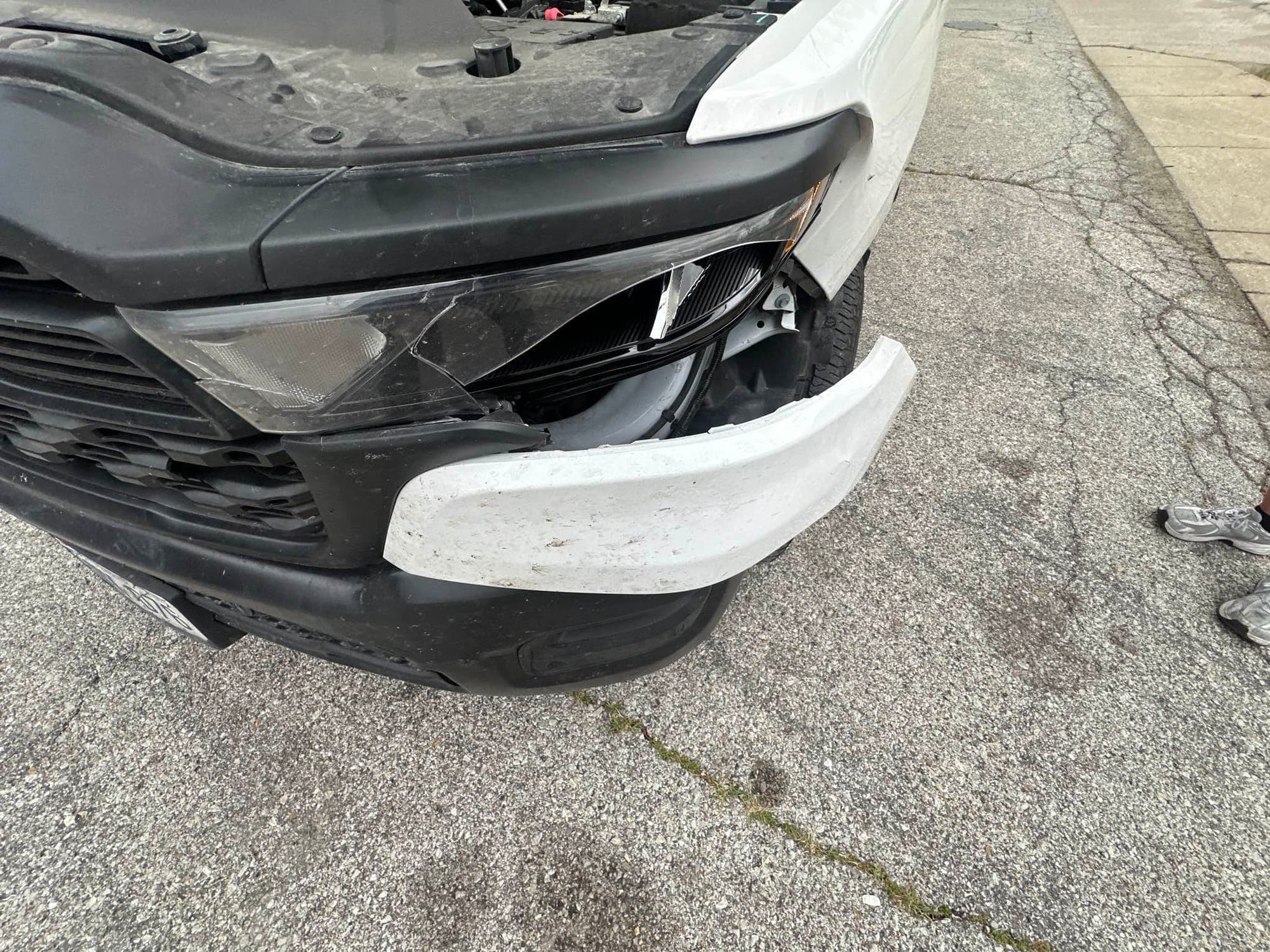 Pickup truck, front corner: before repair. A white pickup with a broken front bumper and grille