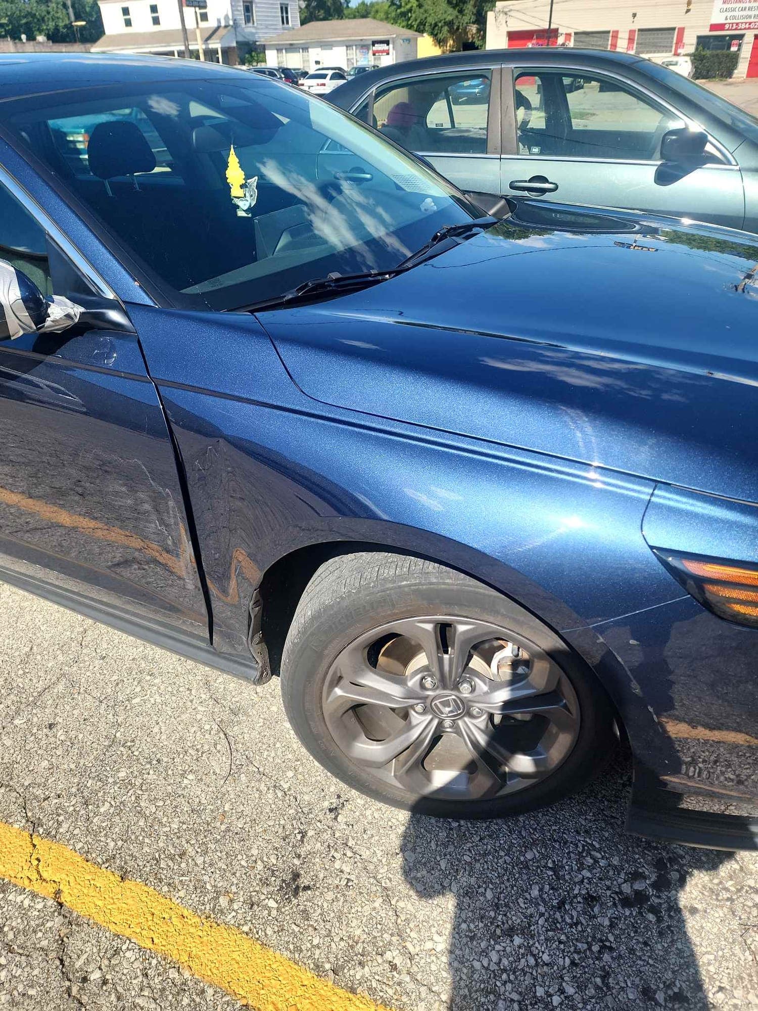 Sedan, fender: before repair. A dark blue sedan with a damaged front fender