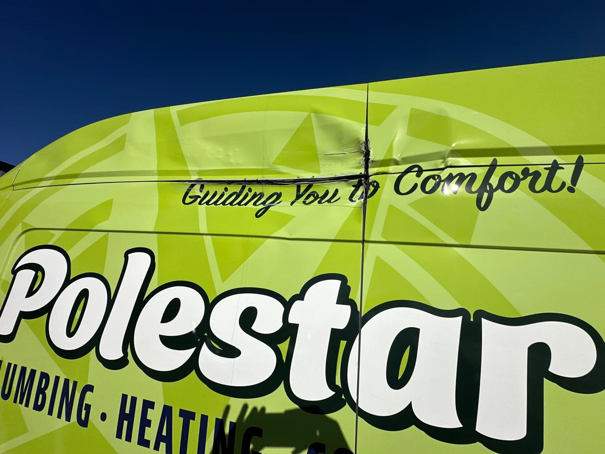 Cargo van, side panel: before repair. A cargo van with a dented panel under its vinyl wrap